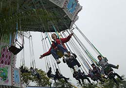 Adult Seth Alberty on kids swing at Ocean Park amusement park in Hong Kong