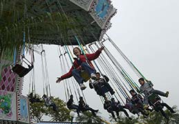 Adult Seth Alberty on kids swing at Ocean Park amusement park in Hong Kong