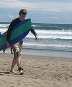 Seth Alberty carrying a surfboard at Kuta Beach, Bali, Indonesia
