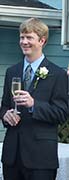 Seth Alberty holding a champagne class listening to a toast at his wedding 