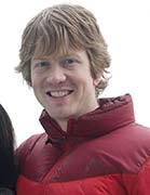 Seth Alberty with long hair and wearing a puffy read coat