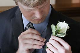 Seth Alberty pinning his corsage to suit on his wedding day