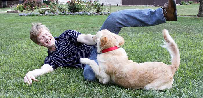 Seth Alberty playing with his golden retriever dog